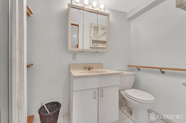 bathroom with toilet, vanity, and tile patterned floors