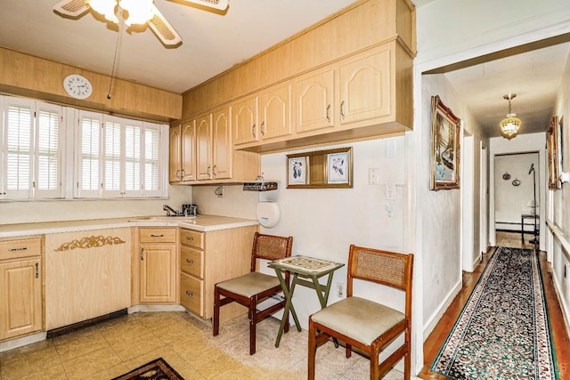 kitchen featuring ceiling fan, decorative light fixtures, light brown cabinets, sink, and a baseboard heating unit