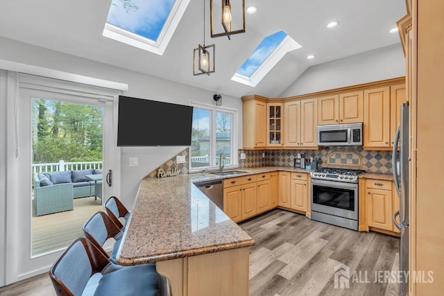 17 Thomas Rd, East Brunswick, NJ 08816 - kitchen featuring appliances with stainless steel finishes, a skylight, a peninsula, light wood-style floors, and lofted ceiling