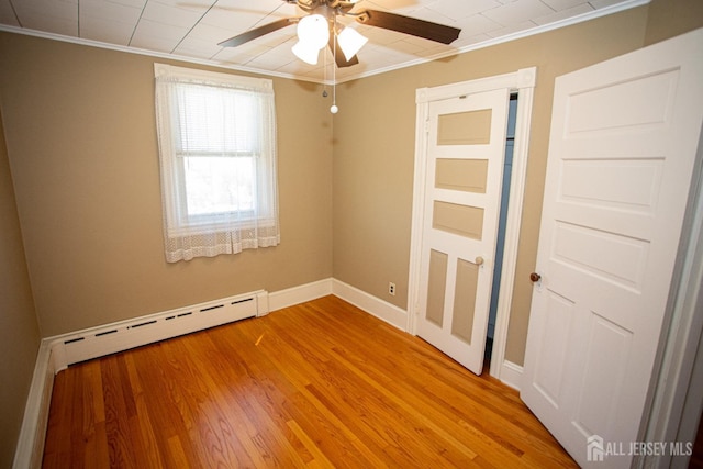 unfurnished room featuring ceiling fan, wood-type flooring, baseboard heating, and ornamental molding