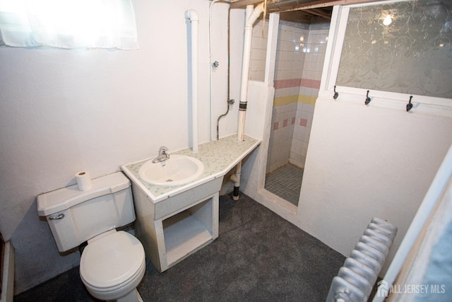 bathroom with vanity, toilet, radiator heating unit, and a tile shower