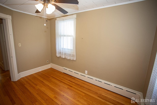 empty room featuring hardwood / wood-style flooring, ceiling fan, crown molding, and baseboard heating