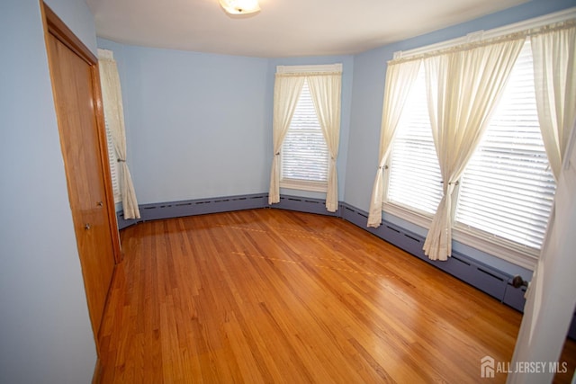 spare room with plenty of natural light, light hardwood / wood-style floors, and a baseboard heating unit