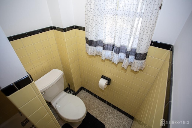 bathroom featuring toilet and tile walls