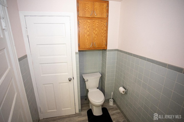 bathroom with wood-type flooring, tile walls, and toilet