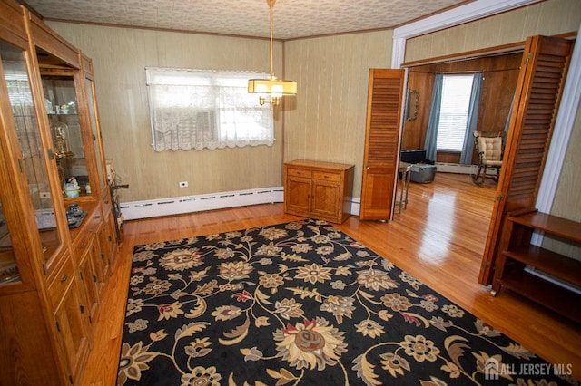 dining room featuring wood-type flooring, baseboard heating, and crown molding