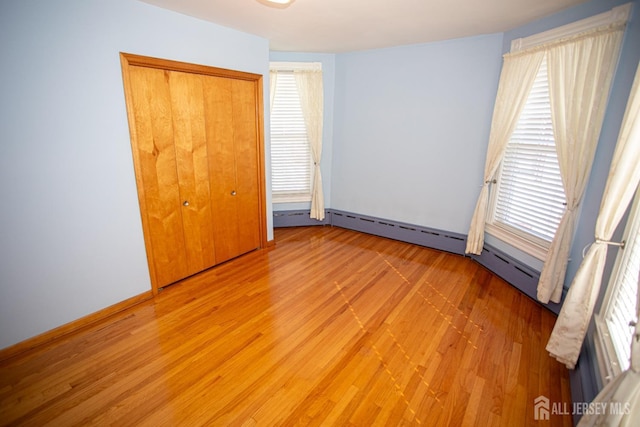 unfurnished bedroom with multiple windows, hardwood / wood-style flooring, and a closet