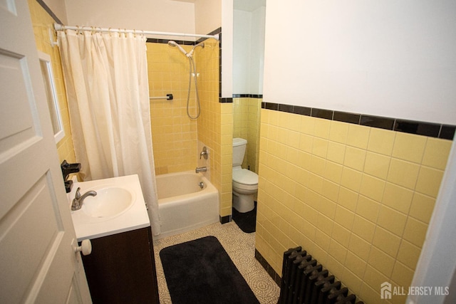 full bathroom with shower / tub combo, vanity, tile walls, radiator heating unit, and toilet