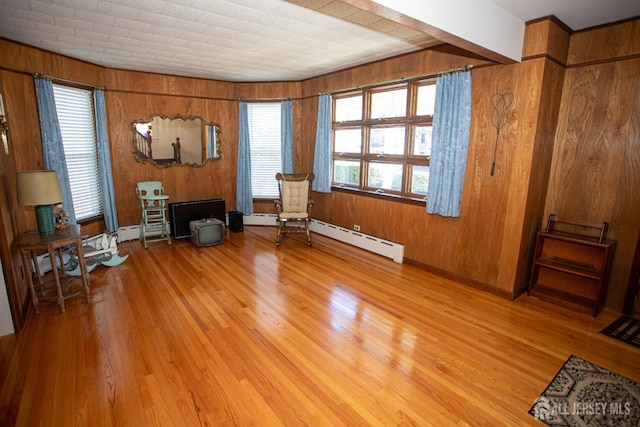 sitting room featuring wood walls, a baseboard radiator, and light hardwood / wood-style floors