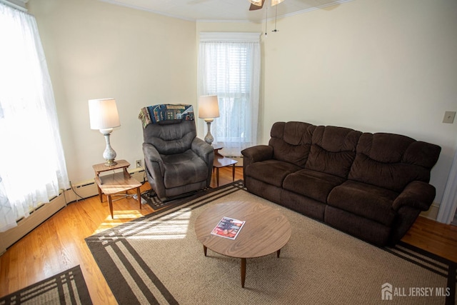 living room with a wealth of natural light, ceiling fan, crown molding, and hardwood / wood-style floors