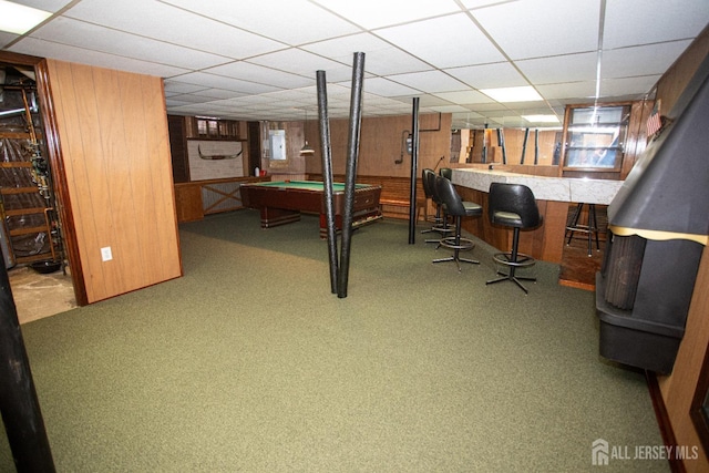 interior space featuring bar area, a paneled ceiling, wood walls, and billiards