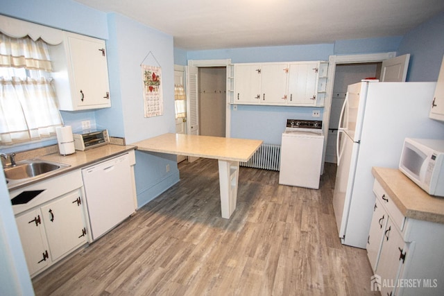 kitchen with radiator, white appliances, sink, white cabinets, and washer / dryer