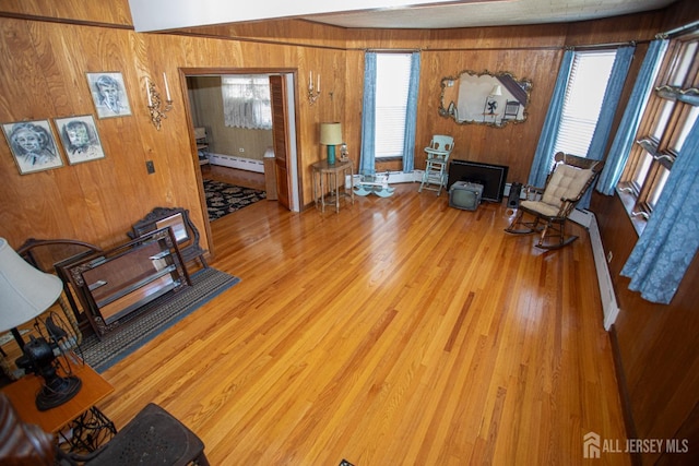 living room with baseboard heating, wooden walls, and hardwood / wood-style flooring