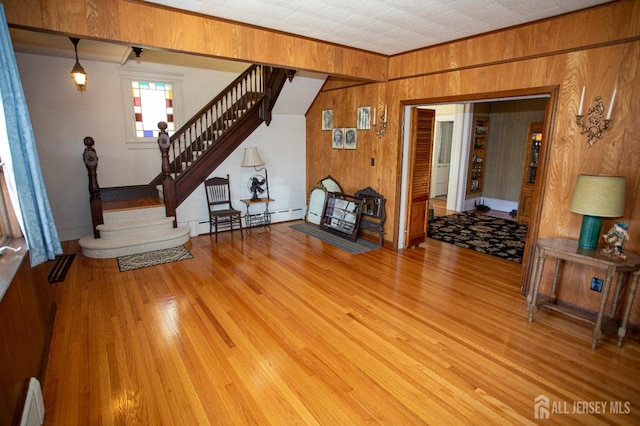 interior space with baseboard heating, wooden walls, and light wood-type flooring