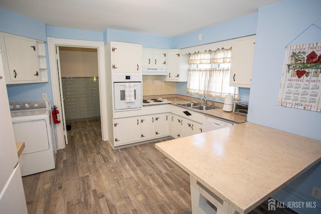 kitchen with kitchen peninsula, white cabinets, white appliances, and washer / dryer