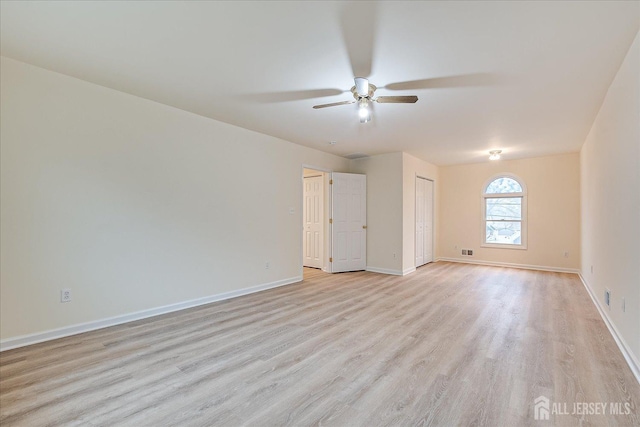 spare room featuring visible vents, baseboards, ceiling fan, and light wood finished floors