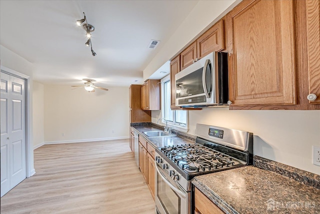 kitchen featuring dark countertops, visible vents, light wood-type flooring, appliances with stainless steel finishes, and a sink