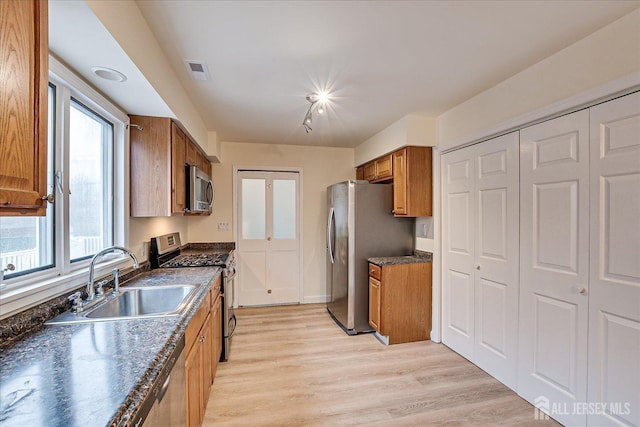 kitchen with visible vents, a sink, dark countertops, appliances with stainless steel finishes, and brown cabinetry