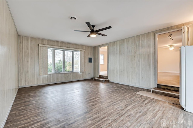 spare room featuring visible vents, baseboards, ceiling fan, and wood finished floors