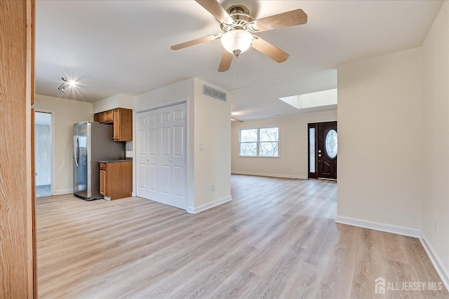 kitchen with light wood finished floors, visible vents, open floor plan, brown cabinets, and freestanding refrigerator