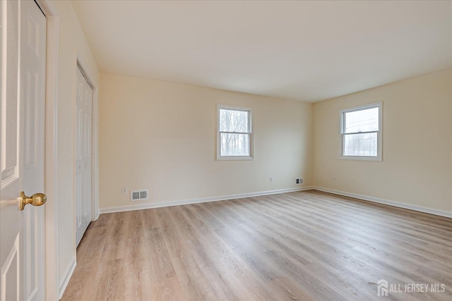 unfurnished bedroom with visible vents, multiple windows, and light wood-style floors