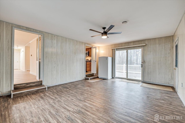 unfurnished living room with visible vents, baseboards, a ceiling fan, and wood finished floors