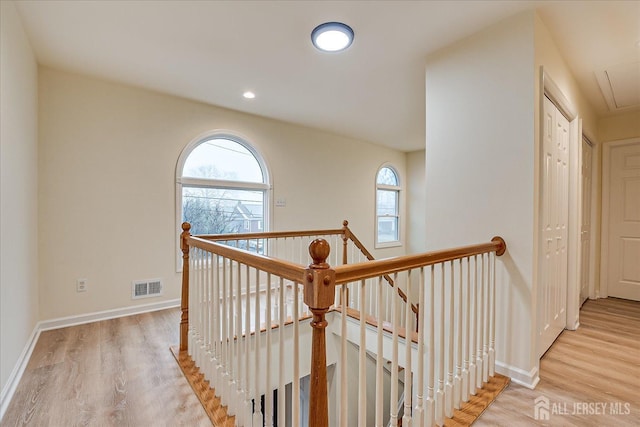 hall featuring an upstairs landing, visible vents, attic access, and wood finished floors