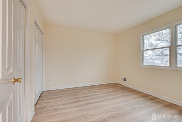 unfurnished bedroom featuring light wood finished floors, visible vents, a closet, and baseboards