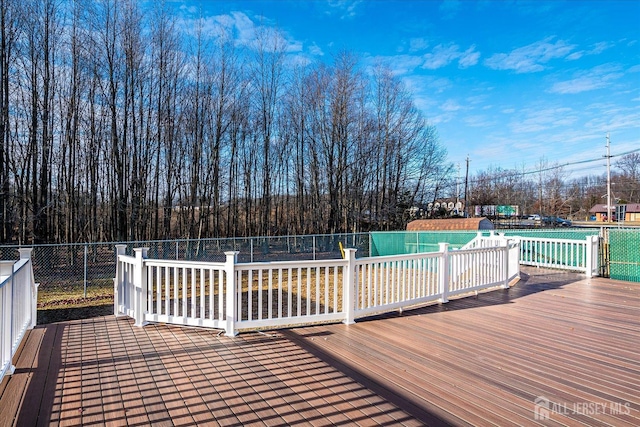 wooden terrace with a fenced in pool and fence