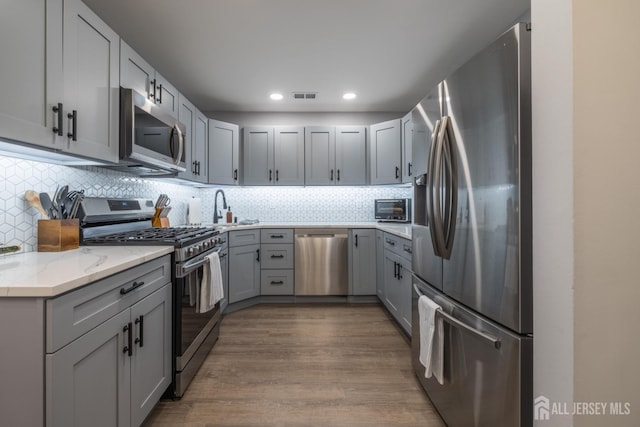 kitchen with stainless steel appliances, decorative backsplash, and gray cabinets