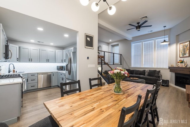 dining room featuring light hardwood / wood-style floors, sink, and ceiling fan