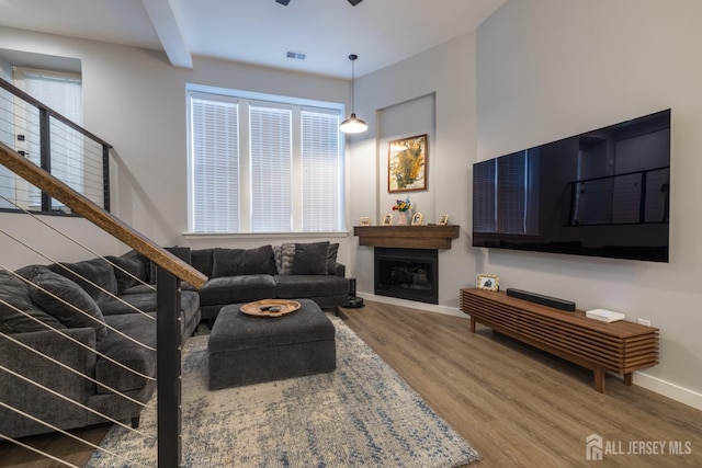 living room featuring wood-type flooring, beamed ceiling, and ceiling fan