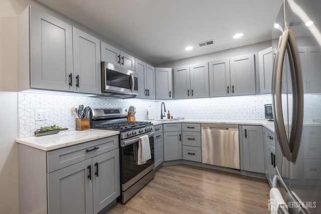 kitchen featuring gray cabinets, tasteful backsplash, and appliances with stainless steel finishes