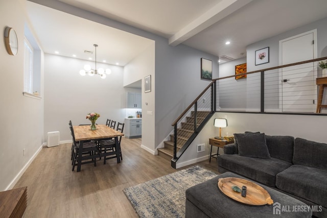 living room with a notable chandelier, beamed ceiling, and light hardwood / wood-style floors