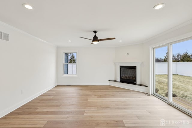 unfurnished living room featuring visible vents, baseboards, ornamental molding, light wood finished floors, and a glass covered fireplace