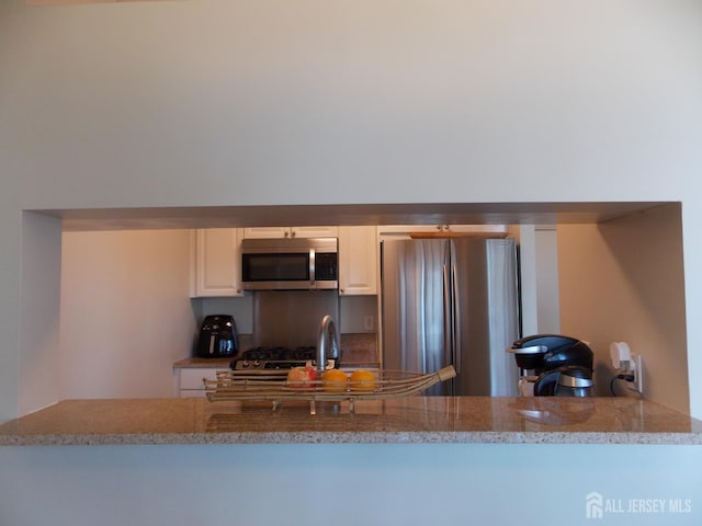 1 Spring St Unit 1205, New Brunswick, NJ 08901 - kitchen with stainless steel appliances, light stone countertops, white cabinets, decorative backsplash, and a sink