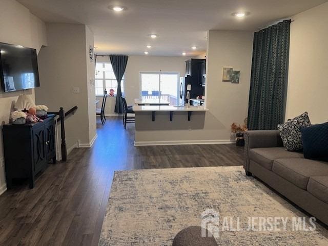 living area featuring recessed lighting, baseboards, and dark wood-style floors