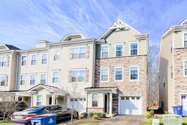 townhome / multi-family property featuring aphalt driveway, an attached garage, and stone siding