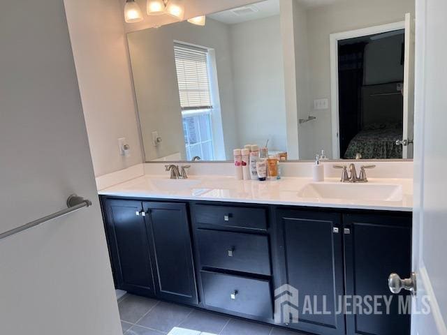 bathroom with tile patterned flooring, double vanity, ensuite bath, and a sink