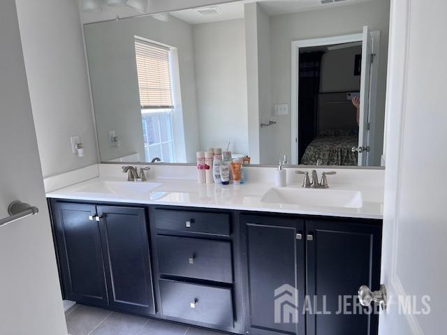 ensuite bathroom featuring double vanity, visible vents, ensuite bathroom, and a sink