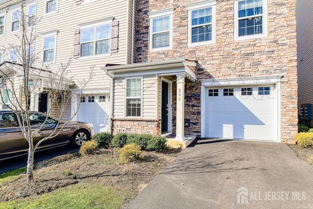 view of front of house with aphalt driveway, stone siding, and a garage