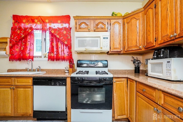 kitchen with white appliances, brown cabinetry, a sink, light stone countertops, and backsplash