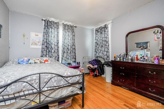 bedroom featuring radiator and wood finished floors