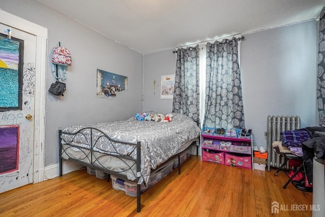 bedroom featuring radiator heating unit and wood finished floors