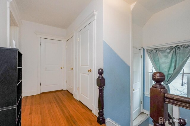 corridor with baseboards, vaulted ceiling, and wood finished floors