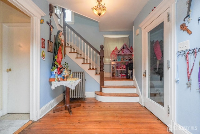 foyer with stairs, radiator heating unit, light wood-type flooring, and baseboards