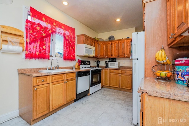 kitchen with brown cabinetry, white appliances, light countertops, and a sink