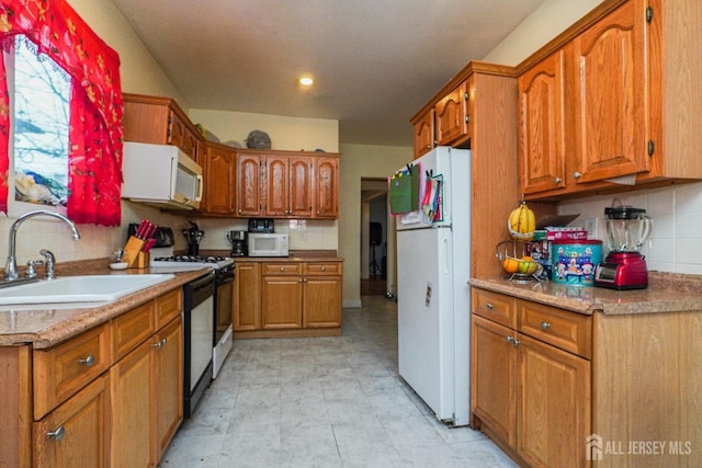 kitchen with light countertops, white appliances, brown cabinetry, and a sink