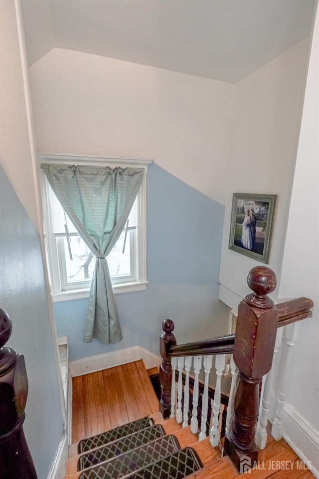 staircase featuring lofted ceiling, wood-type flooring, and baseboards