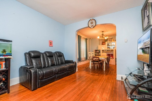 living area featuring arched walkways, baseboards, hardwood / wood-style floors, and an inviting chandelier